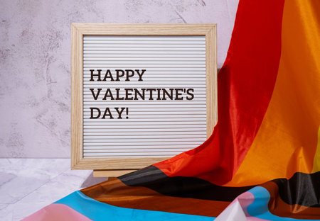 HAPPY VALENTINES DAY text frame on Rainbow LGBTQIA flag made from silk material. Symbol of LGBTQ pride month. Equal rights. peace and freedom. Support LGBTQIA community. diversity equalityの写真素材