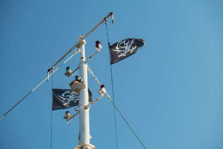 Jolly Roger or pirate ship flag waving with flagpole and blue sky, skull and crossbones, Pirates of the Caribbean sea and Black Pearl. Ripped tearの写真素材