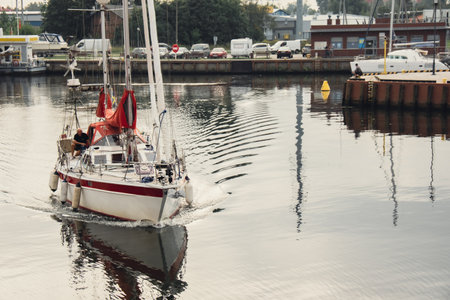 Gdansk, Poland - May 2022 Man resting on sailing private ship against Gdansk Poland city. Man is driving the yacht at sunset Old town tourist destinationのeditorial素材