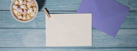 Banner Empty greeting or invitation card mock up violet envelope with white cup of coffee and marshmallows on wooden blue background. Blank paper copy space for your text. Valentines day, Happy fathers mothers day, Womens day holiday. Top view, flat lay minimalist branding conceptの写真素材