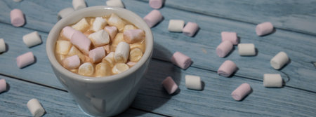 Banner Close up of Cup hot chocolate marshmallows cacao. Cozy Coffee with marshmallows on wooden blue background. Copy space for text. wallpaper design. sweet unhealthy foodの写真素材