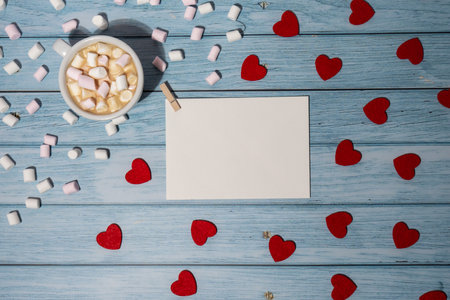 Greeting or invitation card mock up with red hearts with white cup of coffee and marshmallows on wooden background. Romantic Valentine day. Blank paper card copy space for your text. Holiday morning. Top view, flat lay minimalist aesthetic luxury bohemian business branding conceptの写真素材