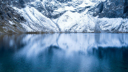 Czarny Staw pod Rysamy or Black Pond lake near the Morskie Oko Snowy Mountain Hut in Polish Tatry mountains, drone view, Zakopane, Poland. Aerial view shot of beautiful green hills and mountains in dark clouds and reflection on the lake Morskie Oko lake. Travel tourist destinationの写真素材