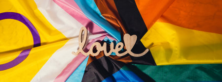 Banner Wooden word love with heart romance on Rainbow LGBTQIA flag made from silk material....