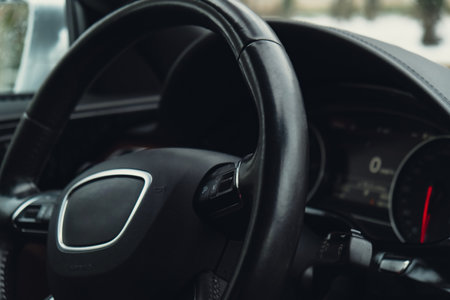 Black luxury modern car Interior. Steering wheel, shift lever and dashboard. Black leather Detail Automatic gear stick. Part of leather seats with stitching in expensive car climate control, speedometerの写真素材