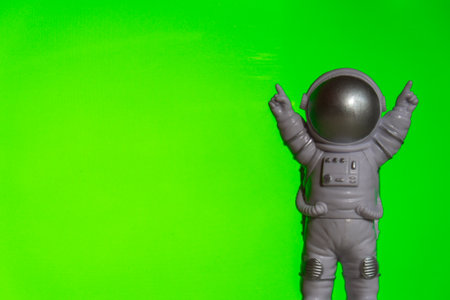 Plastic toy astronaut on green chroma key background Template Mock up Copy space. Concept of out of earth travel, private spaceman commercial flights. Space missions and Sustainabilityの写真素材