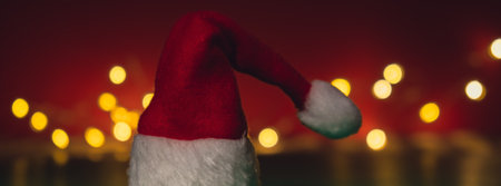 Santa hat on isometric green red background. Defocused lights on backdrop Copy space for your text. Mock up advertisement. Holiday Christmas composition. Minimalist greeting card. Creativeの写真素材