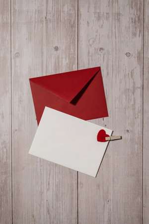 Greeting or invitation card mock up with red envelope on wooden background. Romantic Small hearts Valentine day. Blank paper card copy space for your text. Holiday morningの写真素材