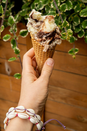 Female hand holding delicious american vanilla chocolate ice cream. Tasty homemade icecream Gelato in the waffle cone. Gluten free vegan dairy freeの写真素材