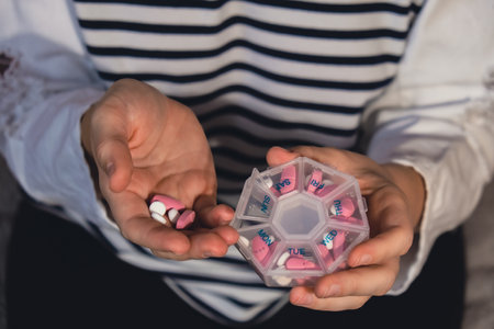 Woman sorting pills Organizer weekly shots Closeup of medical pill box with doses of tablets for daily take medicine with white pink drugs and capsules. Young woman getting her daily vitamins at home. Health care and diseases cureの写真素材