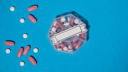Closeup of medical pill box with doses of tablets for daily take medicine with white pink drugs and...