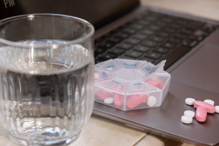 Organizer weekly shots with glass of water on workplace background and laptop Closeup of medical...