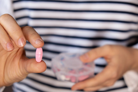 Woman sorting pills Organizer weekly shots Closeup of medical pill box with doses of tablets for daily take medicine with white pink drugs and capsules. Young woman getting her daily vitamins at home. Health care and diseases cureの写真素材