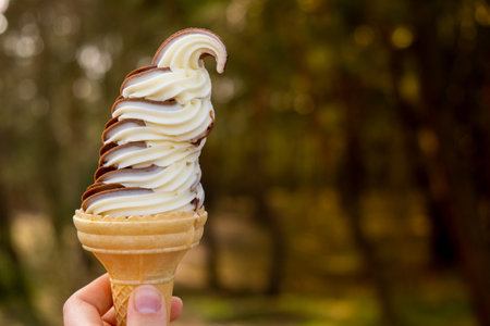 Female hand holding delicious american vanilla chocolate ice cream. Tasty homemade icecream Gelato in the waffle cone. Gluten free vegan dairy freeの写真素材