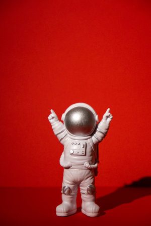 Plastic toy astronaut on colorful red background Copy space. Concept of out of earth travel, private spaceman commercial flights missions and Sustainabilityの写真素材