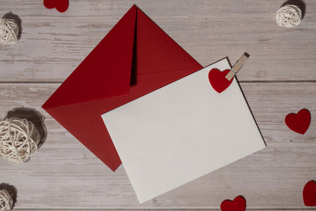 Greeting or invitation card mock up with red envelope on wooden background. Romantic Small hearts Valentine day. Blank paper card copy space for your text. Holiday morningの写真素材