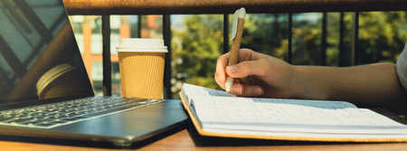 Unrecognizable Young woman study at wooden table in shopping mall food court. Drinking coffee from paper cup. Student making homework Female hands writing on notebook gratitude journal self reflection self discovery in Co-Working Space. Goals, to-do listの写真素材
