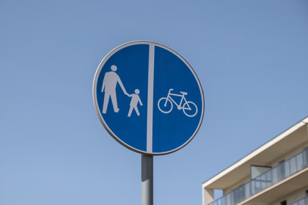 Cyclist and pedestrian route sharing sign. Road sign Pedestrian and bicycle can cross the street here on the background of blue skyの写真素材