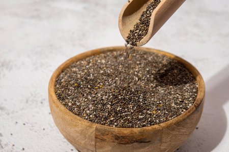 Chia seeds fall in wooden bowl. Healthy superfood rich in Omega 3 fatty acids. Dry healthy natural ingredient. Chia grains are fallingの写真素材
