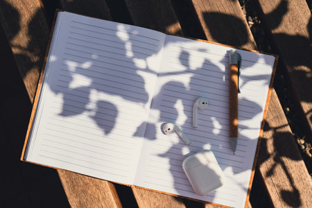 Paper notebook with wireless headphones. Mockup Coffee break. Audio healing, sound therapy wellness rituals, positive mental health habits listening podcast writing self discovery gratitude journal. Making plans for next week year. Being mindful reducing stressの写真素材