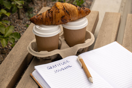 Writing Gratitude Journal on wooden bench. Coffee and croissants morning routine. Today I am grateful for. Self discovery journal, self reflection creative writing, self growth personal development concept. Wellbeing spiritual health, being mindful, holistic health practicesの写真素材