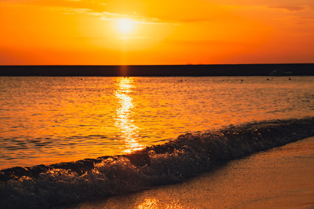 Reflection of sunlight over sea surface at sunset. Orange and gold blue sky. Dramatic Yellow sun...