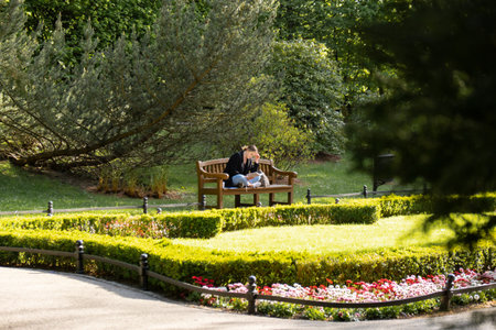 Attractive young woman reading book while sitting on grass in green public park. Springtime outdoors. Greenery unity with nature. Spend free time on open airの写真素材