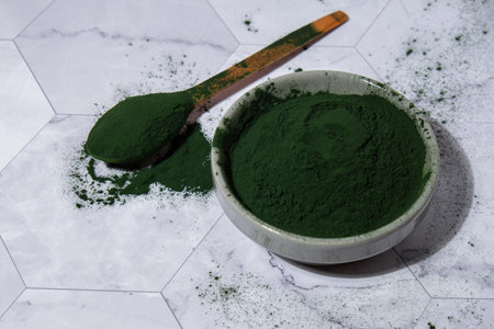 Blue-green algae Chlorella and spirulina powder in bowl with wooden spoon. Super powder. Natural...