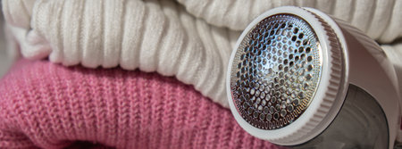 Anti-pilling razor. Device for shaving clothes. Anti-Plush fabric Shaver. Electric portable sweater pill defuzzer Lint remover from pink acrylic or wool sweater. Electric device fabric shaver after cleaning and collected fluffの写真素材