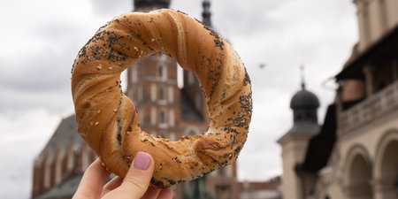 Tourist woman eating bagel obwarzanek traditional polish cuisine snack waling on Market square St....