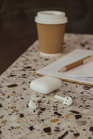 Take away coffee in craft recycling paper cup with paper notebook with wireless headphones. Mockup Coffee break. Audio healing, sound therapy wellness rituals, positive mental health habits listening podcast writing self discovery gratitude journal. Making plans for next week year. Being mindful reducing stressの写真素材