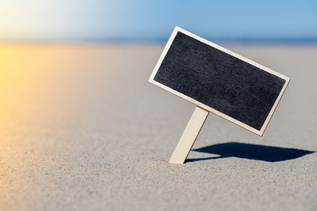 Empty blackboard frame board with copy space for your text or design displays on sandy beach. Summer vacation and holiday business travel concept. Template Mock up for sale promotion advertisementの写真素材