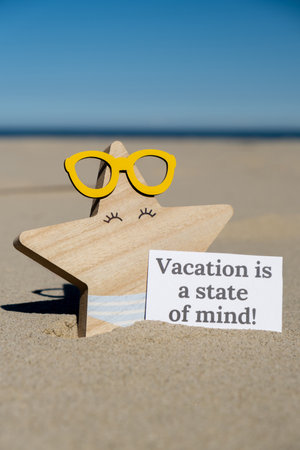 VACATION IS A STATE OF MIND text on paper greeting card on background of funny starfish in glasses summer vacation decor. Sandy beach sun coast. Holiday concept postcard. Getting away Travelの写真素材