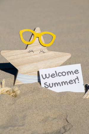 WELCOME SUMMER text on paper greeting card on background of funny starfish in glasses summer vacation decor. Sandy beach sun coast. Holiday concept postcard. Getting away Travelの写真素材