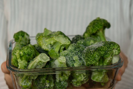Unrecognizable woman showing into camera frozen food broccoli florets homemade. Harvesting concept. Stocking up vegetables for winter storageの写真素材