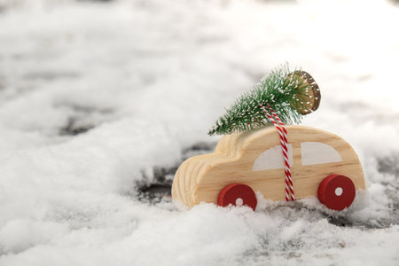 Wooden car carrying Christmas tree over snow. Copy space for text Toy car in snowy landscape. Merry Christmas and Happy New Year conceptの写真素材