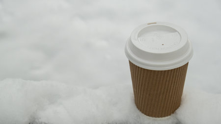 Hot warming drink in Eco paper cup. Mock up Cardboard coffee or tea Cup in the snow in winter day. Copy space zero waste recycle cup white snow-covered fieldの写真素材