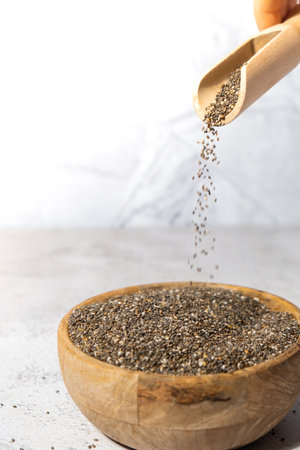 Chia seeds fall in wooden bowl. Healthy superfood rich in Omega 3 fatty acids. Dry healthy natural ingredient. Chia grains are fallingの写真素材