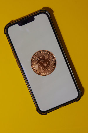 Bitcoin gold coin on mobile phone with white screen. Mining trading concept. BTC golden money. Worldwide virtual internet Cryptocurrency or crypto digital payment system. Digital coin money farmの写真素材