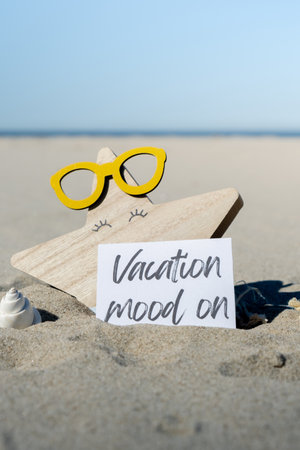 VACATION MOOD ON text on paper greeting card on background of beach chair lounge starfish summer vacation decor. Sandy beach sun. Holiday concept postcard. Travelの写真素材