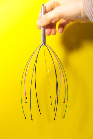 Scalp massager for home. Close up of scalp massaging brush for hair growing routine. Anti stress acupuncture metal octopus tool equipment. Manual device for home Medicine and cosmetologyの写真素材