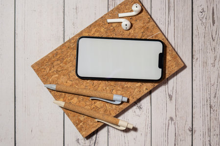 Top view, wooden Office desk mobile phone chroma key screen mock up mobile app application eco pen, wireless headphones and recycle notebook. Business or student workspace concept Flat lay. Modern technology Personal diary Audio healingの写真素材