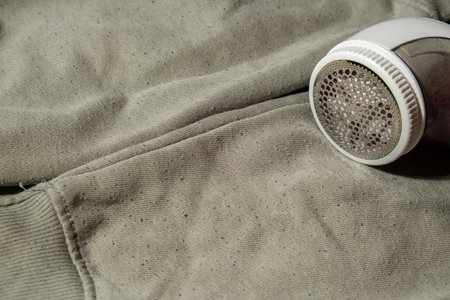 Anti-pilling razor. Device for shaving pellets clothes. Anti-Plush fabric Shaver. Electric portable sweater pill defuzzer Lint remover from acrylic or wool sweater. Sustainability lifestyle fashion, reducing clothing wasteの写真素材