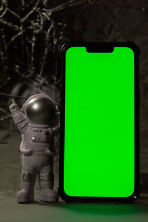Plastic toy figure astronaut with mobile phone chroma key green screen for your advertisement Copy...