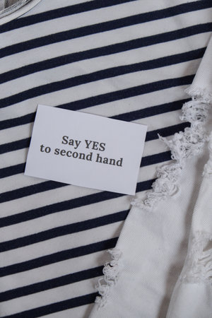 SAY YES TO SECOND HAND text on paper note on clothes assortment Second hand sustainable shopping....