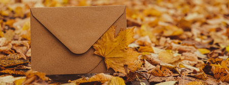Empty earth tones envelope mock up around Colorful falling autumn leaves. Template card. Golden tree leaves. Beautiful tree with yellow leaves in autumn forest. Path littered with autumn leaves. Nature fall landscapeの写真素材