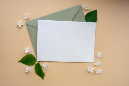 Composition with empty envelope and beautiful spring lilac flowers on beige background. Mockup card invitation greeting card postcard copy space template. Branches of lilac blooming bouquet.の写真素材