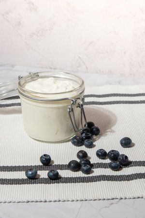 Glass jar with natural organic homemade yogurt and blueberries on table. Immunity-boosting ingredients. Concept of healthy eating breakfast of Greek yogurt. Fermenting superfoodの写真素材