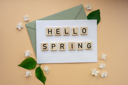 HELLO SPRING text on Composition with envelope and beautiful spring lilac flowers on beige background.. Branches of lilac blooming bouquetの写真素材