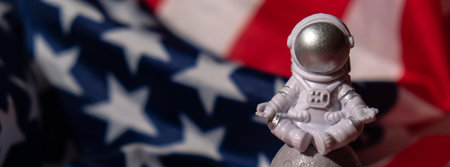 Plastic toy figure astronaut on American flag background Copy space. 50th Anniversary of USA Landing on The Moon Concept of out of earth travel, private spaceman commercial flights missions and Sustainabilityの写真素材